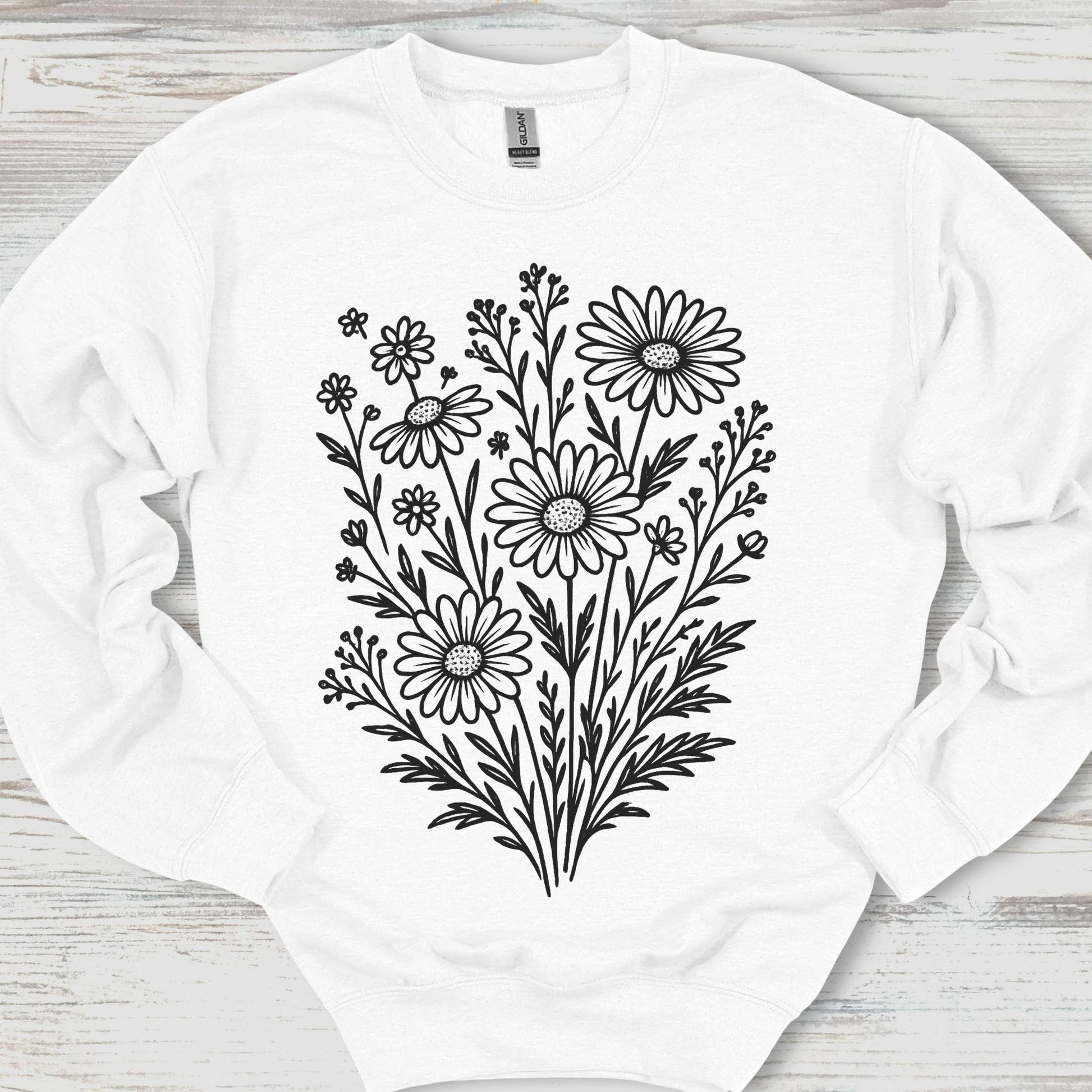 White sweatshirt with black floral design on a wooden surface