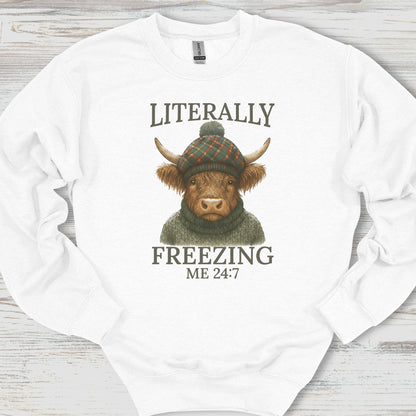 White sweatshirt with a highland cow graphic and text on a wooden surface