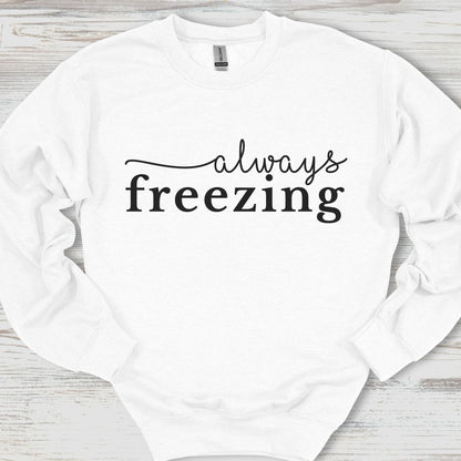 White sweatshirt with 'always freezing' text on a wooden surface