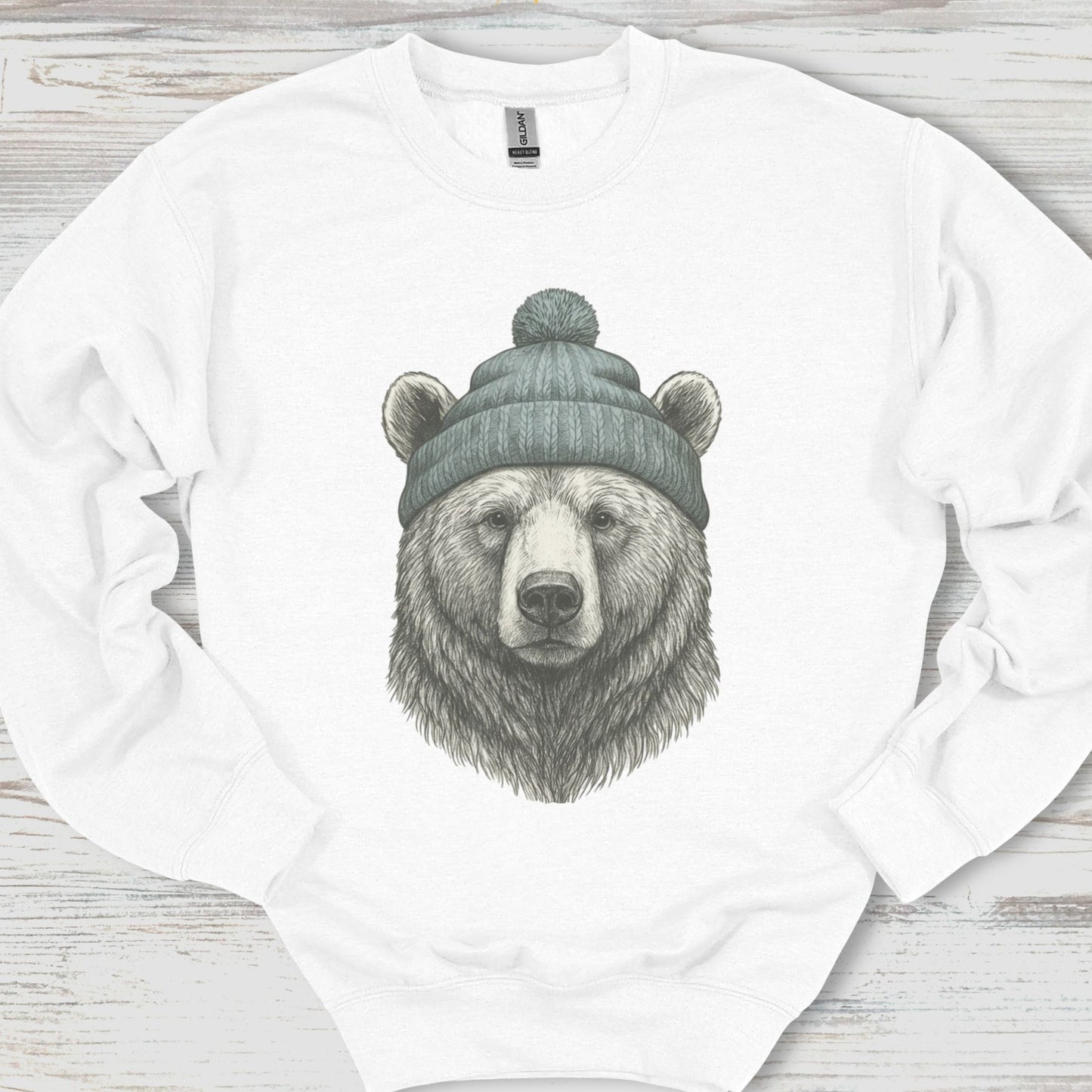 White sweatshirt with a bear wearing a beanie design on a wooden surface