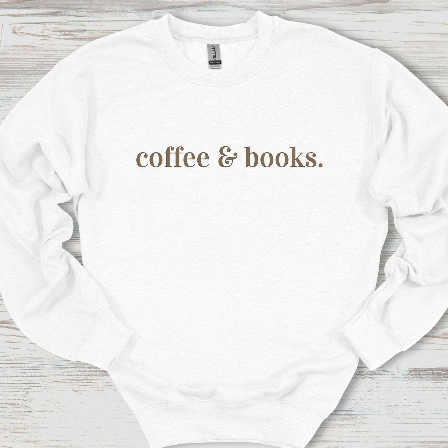 White sweatshirt with 'coffee & books.' text on a wooden surface